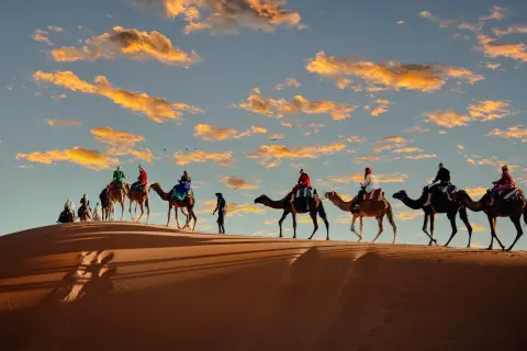 Tours privados pelo Marrocos – Caravana de camelos atravessando as dunas do Saara ao pôr do sol